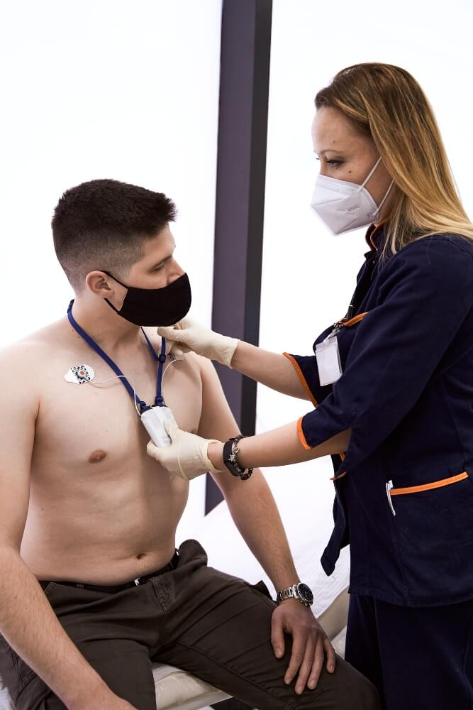 A medical nurse puts a holter device on a patient