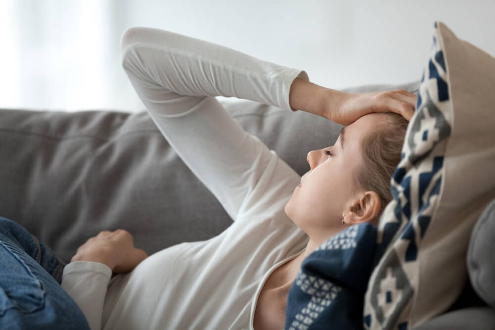 Žena sa glavoboljom leži na sofi